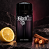 Paco Rabanne Black XS on dark textured stone beside a large lemon slice, cinnamon sticks, and caramelized pralines under muted plum lighting.
