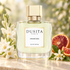 Parfums Dusita Anamcara on ivory stone beside white tuberose, orange blossoms, and sliced blood orange in soft golden garden light.