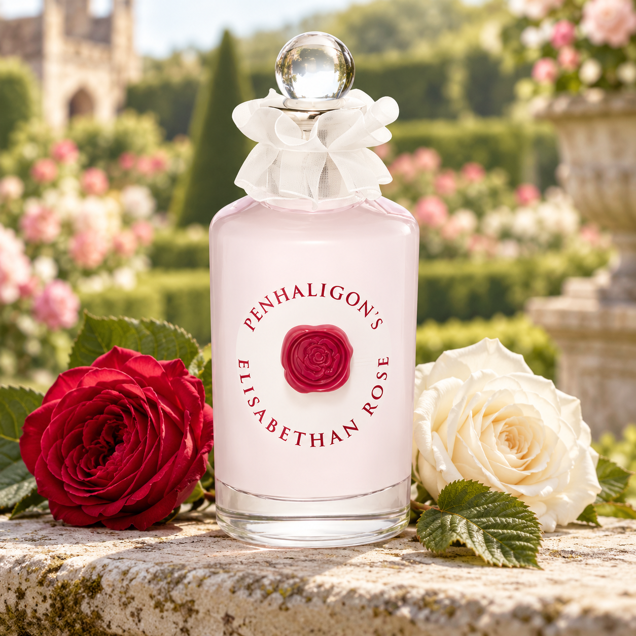 Penhaligon’s Elisabethan Rose bottle with red and white roses and hazelnut leaves on sunlit stone in a formal garden.