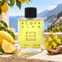 Profumum Roma Acqua Viva stands beside Amalfi lemons, yellow broom flowers, and cedarwood on a sunlit terrace overlooking the coast.