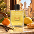 Profumum Roma Dulcis in Fundo bottle with whole mandarin, lemon, vanilla pods and pastry on a sunlit Roman café table.