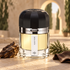 Ramon Monegal Agar Musk on warm limestone beside agarwood, cypress, and brown leather, with a softly blurred Moorish arch behind it.