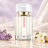 Ramon Monegal Atractone Musk on ivory stone beside lilac, white jasmine, and sandalwood, with soft cream fabric and a pale lavender backdrop.