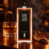 Serge Lutens Écrin de Fumée bottle beside a glass of amber rum and tobacco leaf on dark wood with soft smoke.