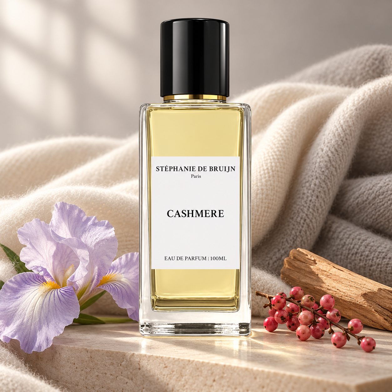 Stéphanie de Bruijn Cashmere beside a lavender iris, pink berries, and sandalwood, framed by ivory cashmere in soft sunlight.