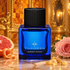 Cobalt blue Thameen Amber Room bottle beside grapefruit, a pink rose, and frankincense resin, with glowing amber panels and gold-framed mirrors behind it.