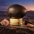 The House of Oud Blessing Silence on sandstone beside a blush rose, oud, and sandalwood, overlooking quiet desert dunes at dusk.