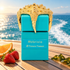 Turquoise Tiziana Terenzi Abbrivio bottle with a gold starfish cap on a sunlit yacht deck, beside orange, strawberries, and seaweed.