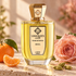 Unique’e Luxury Beril beside mandarin, a blush rose, and cardamom pods on warm travertine in golden sunlight.