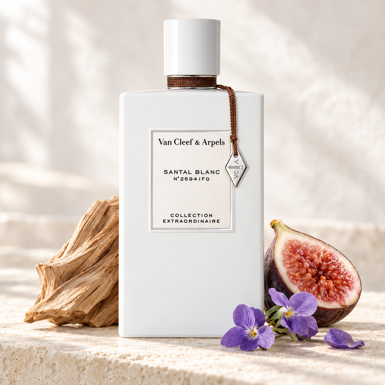 Van Cleef & Arpels Santal Blanc with sandalwood, a halved fig, and violet flowers on sunlit ivory stone.