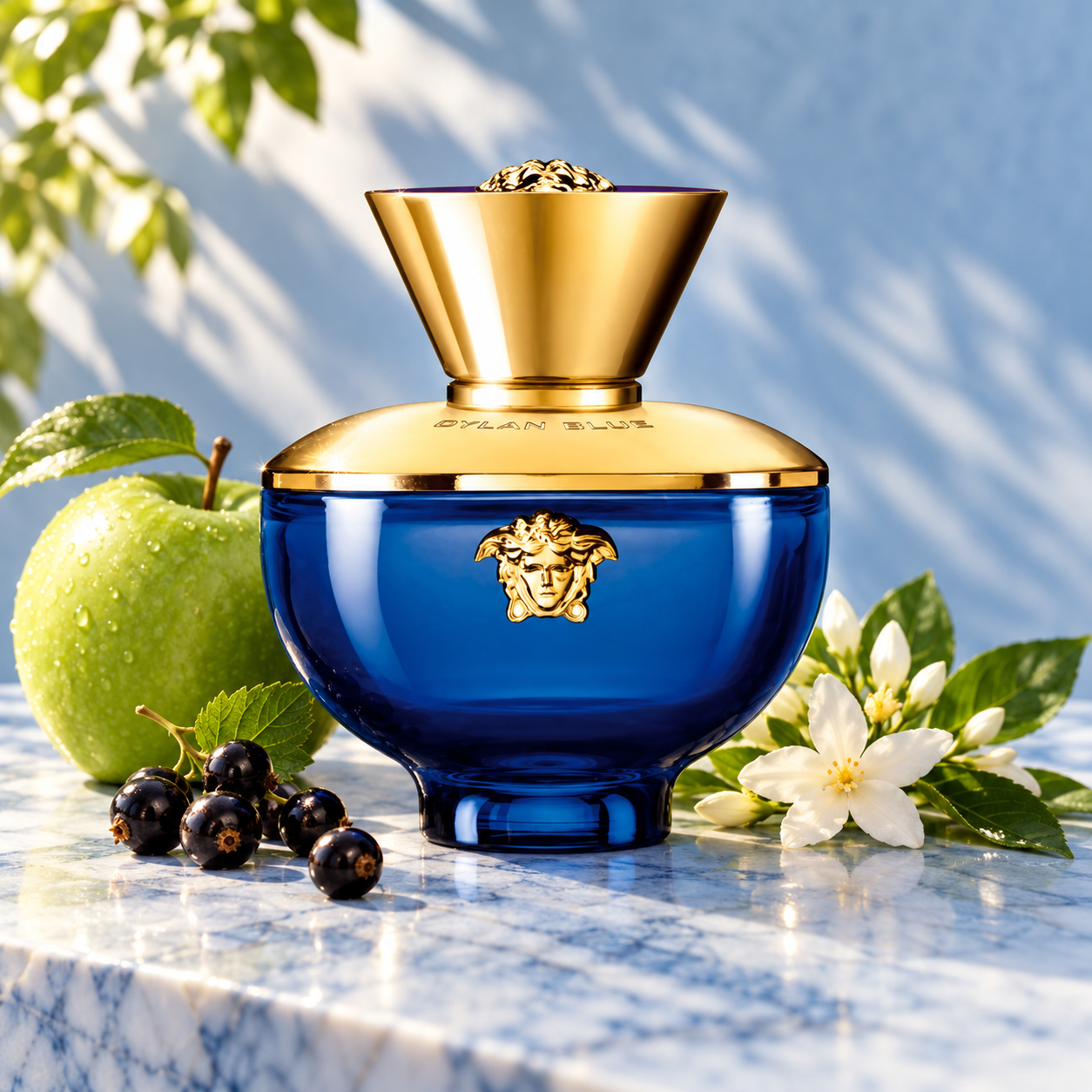 Versace Dylan Blue Pour Femme bottle with whole green apple, blackcurrants and jasmine on sunlit blue marble.