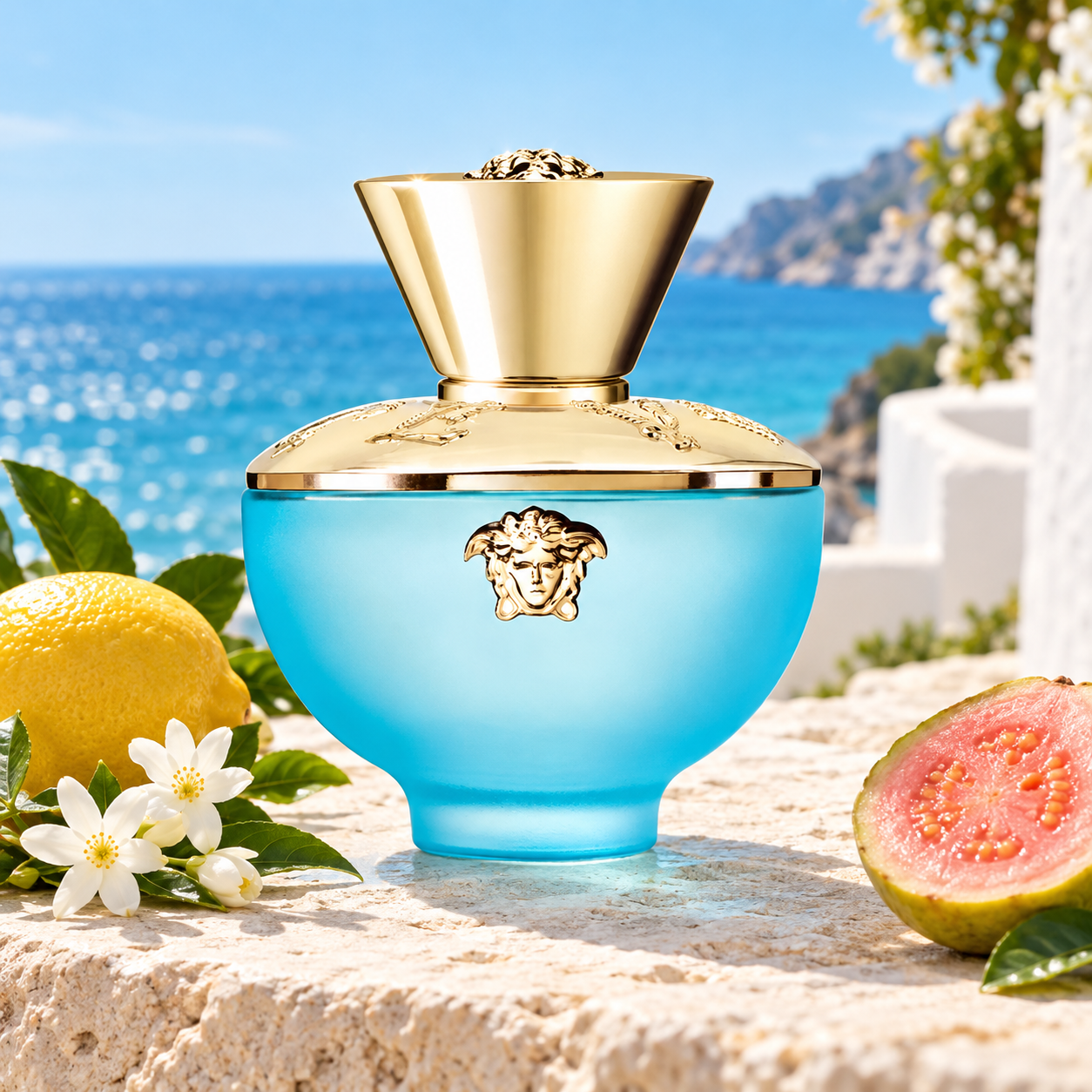 Versace Dylan Turquoise Pour Femme bottle with whole lemon, jasmine and a guava half on sunlit limestone beside blue sea.