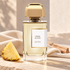 BDK Crème de Cuir perfume bottle beside a pineapple wedge, ivory fabric and pale wood in warm sunlight.