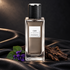 Yves Saint Laurent Cuir bottle on black leather beside oud wood and violet leaves in soft dramatic light.