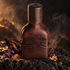 Orto Parisi Cuoium leather-wrapped bottle on dark volcanic stone beside charred cedar, violet flowers and incense resin with a faint smoky background.