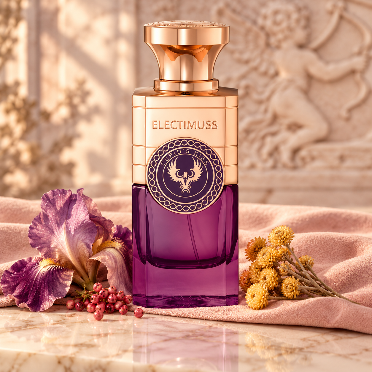 Electimuss Cupid's Kiss purple and rose-gold bottle on blush suede beside iris, golden immortelle and pink pepper in soft romantic light.