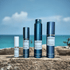 ScentsGift 2 ml, 5 ml, 8 ml, and 10 ml perfume decant atomizers on a stone ledge overlooking turquoise water.