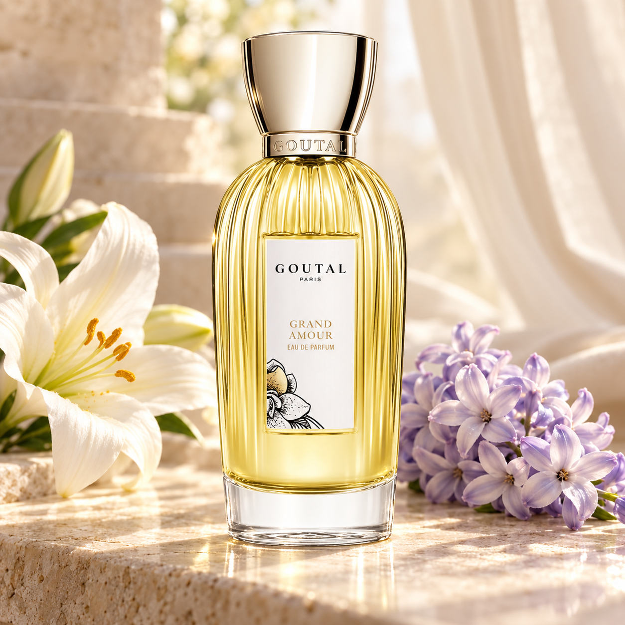 Goutal Grand Amour bottle beside white lily and pale purple hyacinth on ivory stone in soft daylight.