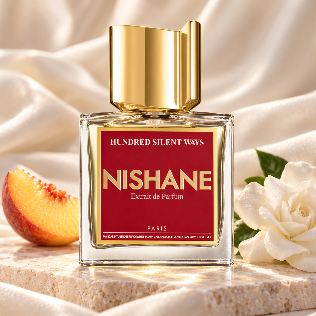 Nishane Hundred Silent Ways on pale stone with a peach wedge and gardenia against ivory silk.