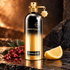 Montale Intense Pepper on dark stone with pink pepper berries and a lemon wedge in warm light.