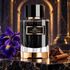 Carolina Herrera Iris Empire bottle on dark marble beside purple irises, chocolate and cinnamon, with a softly lit arch behind.