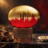 The House of Oud CROP 2023 gold and red bottle beside oud wood and white peppercorns on dark stone in warm lighting.